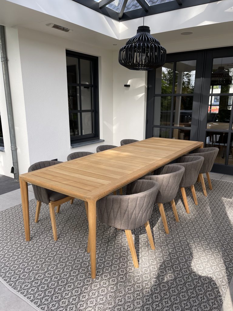 Houten tafel met grijze stoelen in veranda.