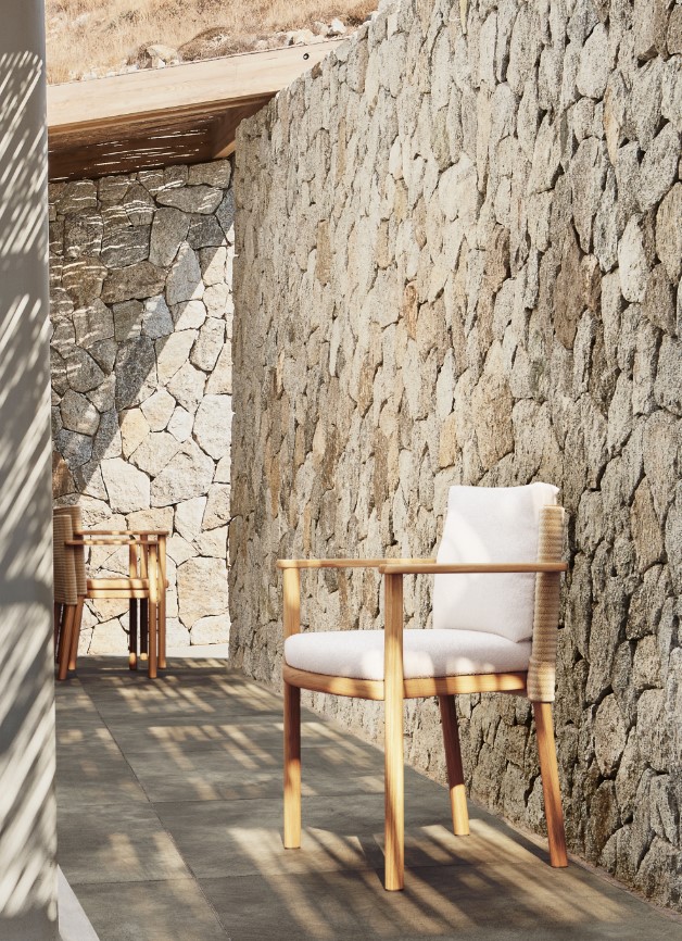 Houten stoel bij stenen muur in zonlicht.