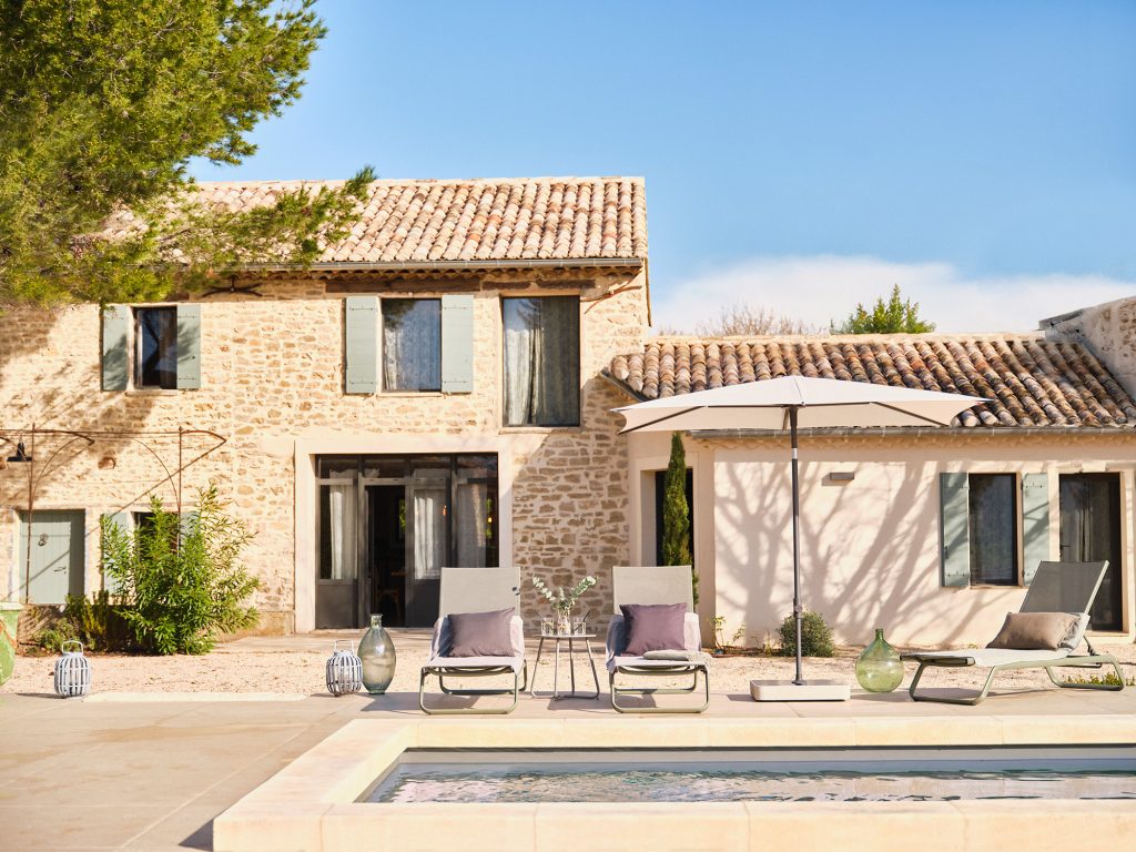 Stenen huis met zwembad en ligstoelen buiten.