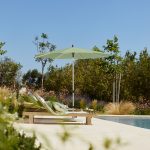 Ligbedden langs zwembad met groene parasol