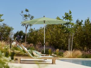 Ligbedden langs zwembad met groene parasol