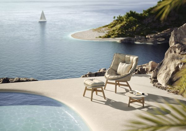 Relaxstoel bij zwembad met uitzicht op zee.