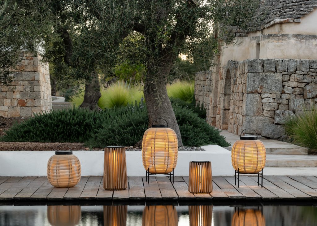 Buitenlantaarns langs zwembad, stenen muren op achtergrond.