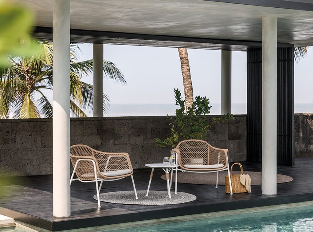 Loungehoek bij zwembad met palmbomen.